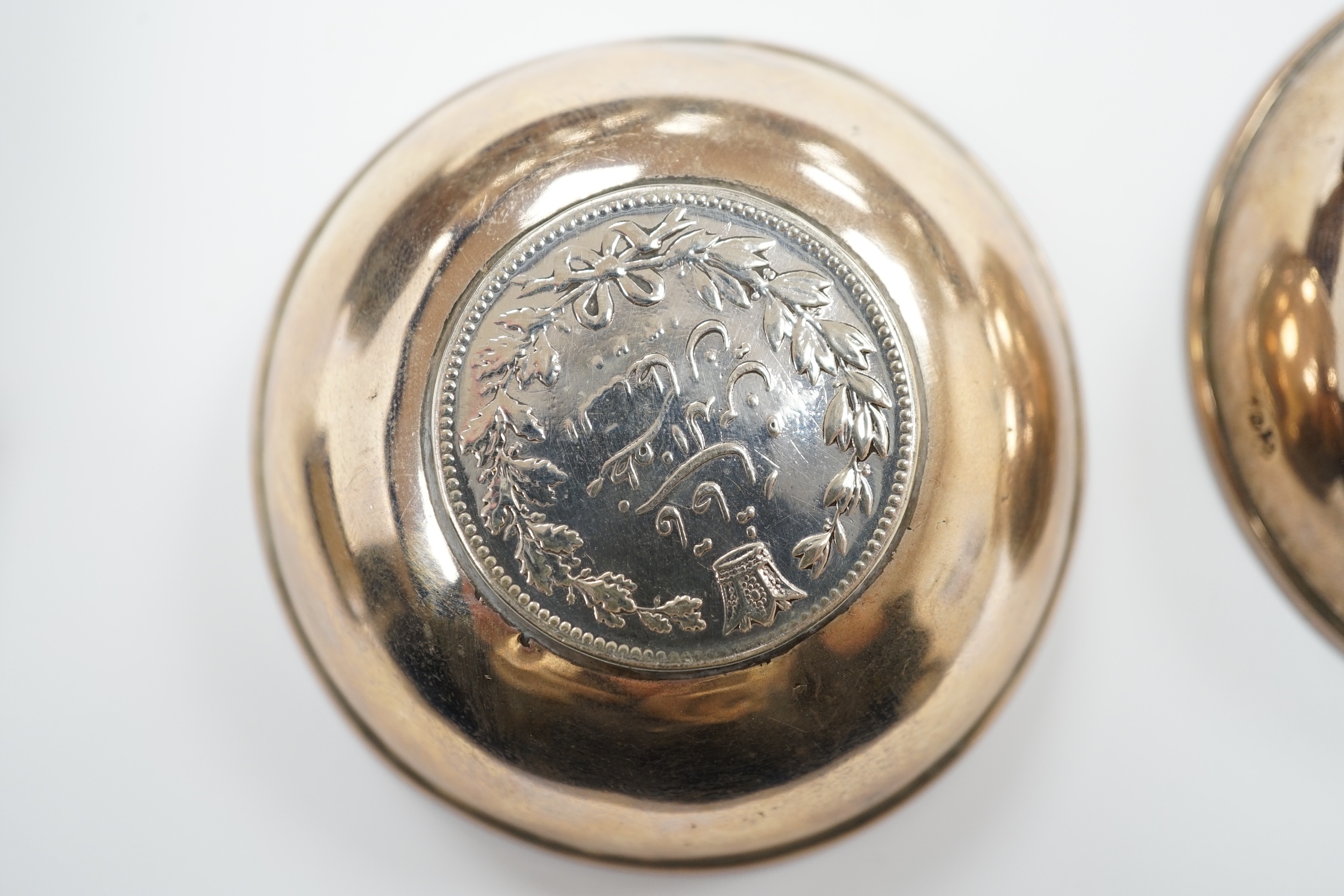 A Tibetan white metal mounted cup, two coin inset dishes and a silver matchbox holder, largest 11.5cm diameter